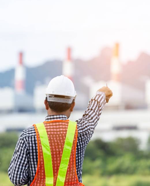 Engineer with a coal power plant in the background, Thailand.